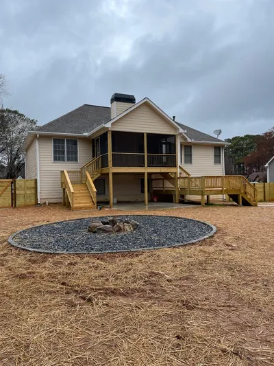 Finished deck and screened porch at a residential home with a circular gravel fire pit area in the backyard