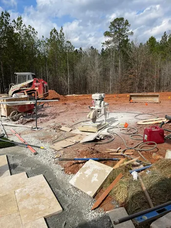 Hardscape construction site with travertine tiles staged and equipment at a new residential build