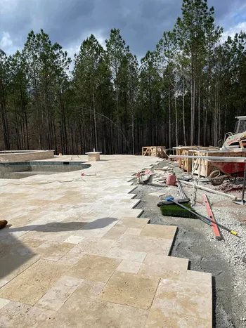 Travertine tile pool deck installation in progress at a new construction residential property
