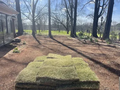 Image of a pile of sod ready to be installed onto a bare yard.  